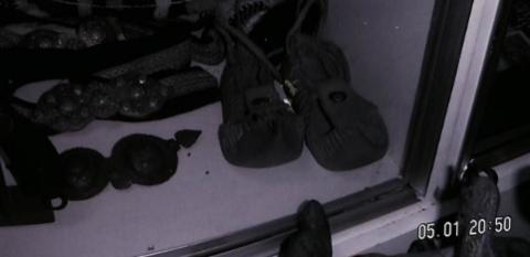 Ασπρόμαυρη φωτογραφία παλιού παραδοσιακού υποδήματος. Επίσης αχνοφαίνονται ζωνάρια με λεπτομέρειες.