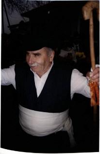 Κάτοικος Καλής Βρύσης Στέφανος Κάλλιας με παραδοσιακή ενδυμασία. Ηλικιωμένος άνδρας φοράει λευκό πουκάμισο, λευκο ζωνάρι, μαύρο παντελόνι και μαυρο γιλέκο. Στο κεφάλι φοράει τραγιάσκα